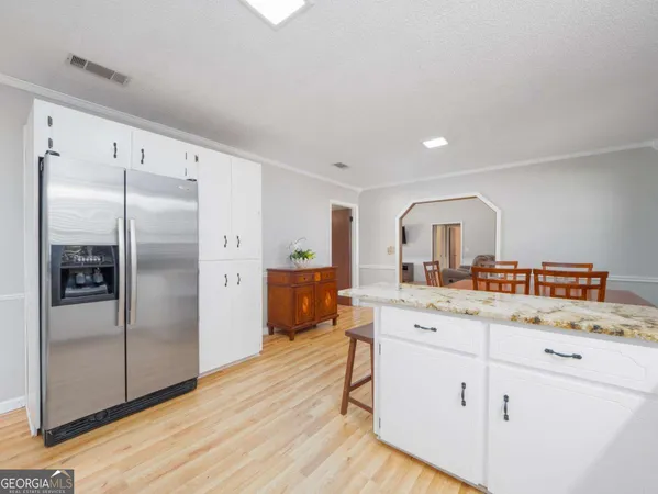 a kitchen with cabinets a sink dishwasher a dining table and chairs with wooden floor