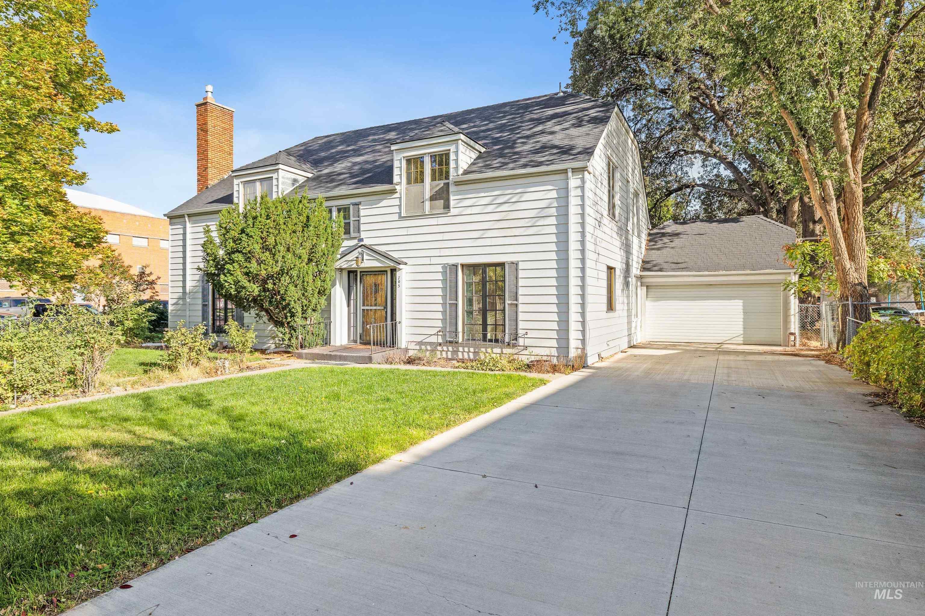 View of front of house with a chimney and a garage