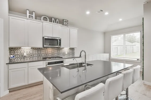 a kitchen with stainless steel appliances granite countertop a sink a microwave and wooden cabinets