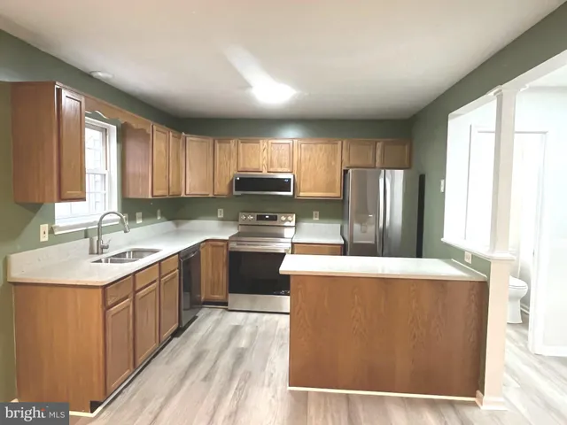 a kitchen with stainless steel appliances granite countertop a refrigerator a sink a stove a microwave and island with wooden cabinets