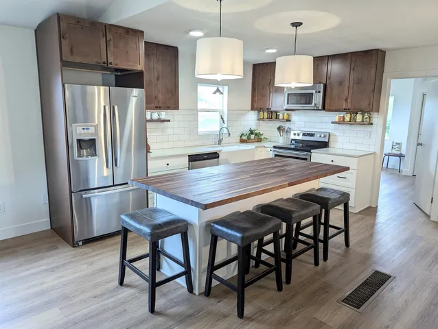 a kitchen with granite countertop a wooden floor and stainless steel appliances