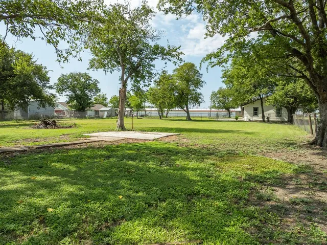 a view of a green field with trees in the background