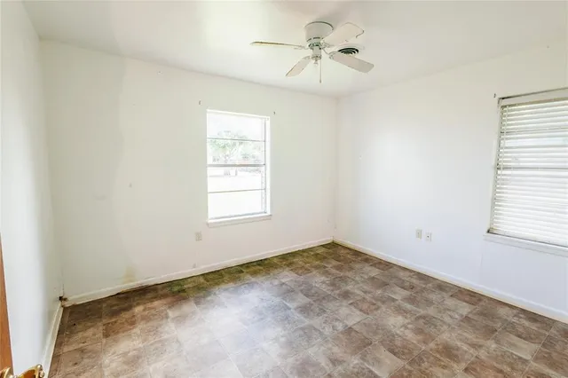 an empty room with windows and fan
