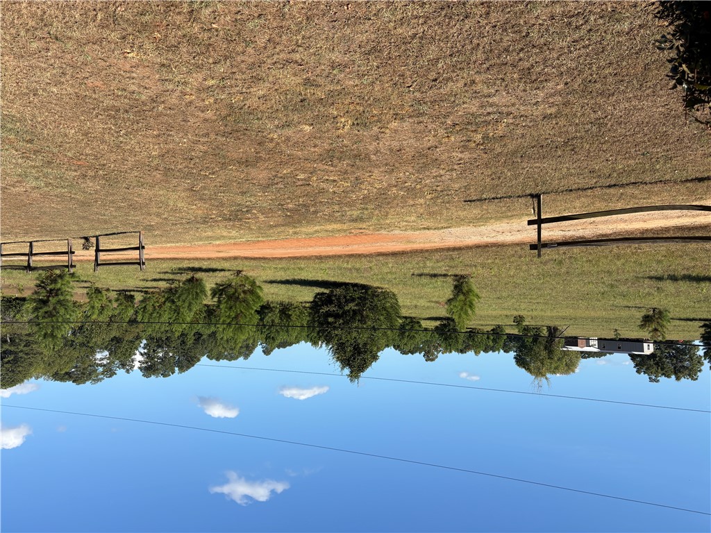 1108 Trotter Road Anderson, SC 29626 - Photo 27 of 27 Fenced pastures and mature trees line the horizon under a clear blue sky.