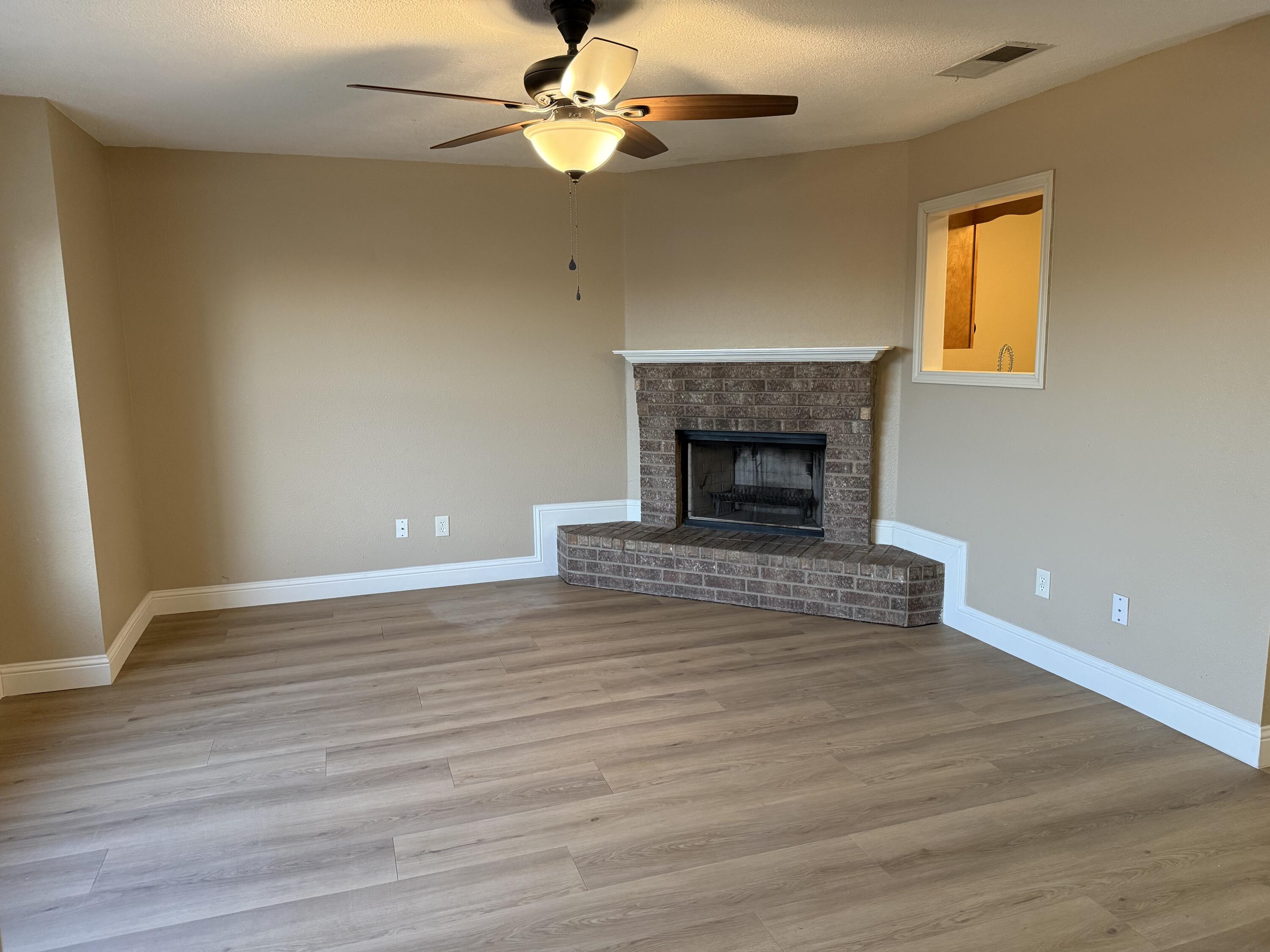 2523 110th Street Lubbock, TX 79423 - Photo 3 of 23 a view of an empty room with wooden floor fireplace and a window