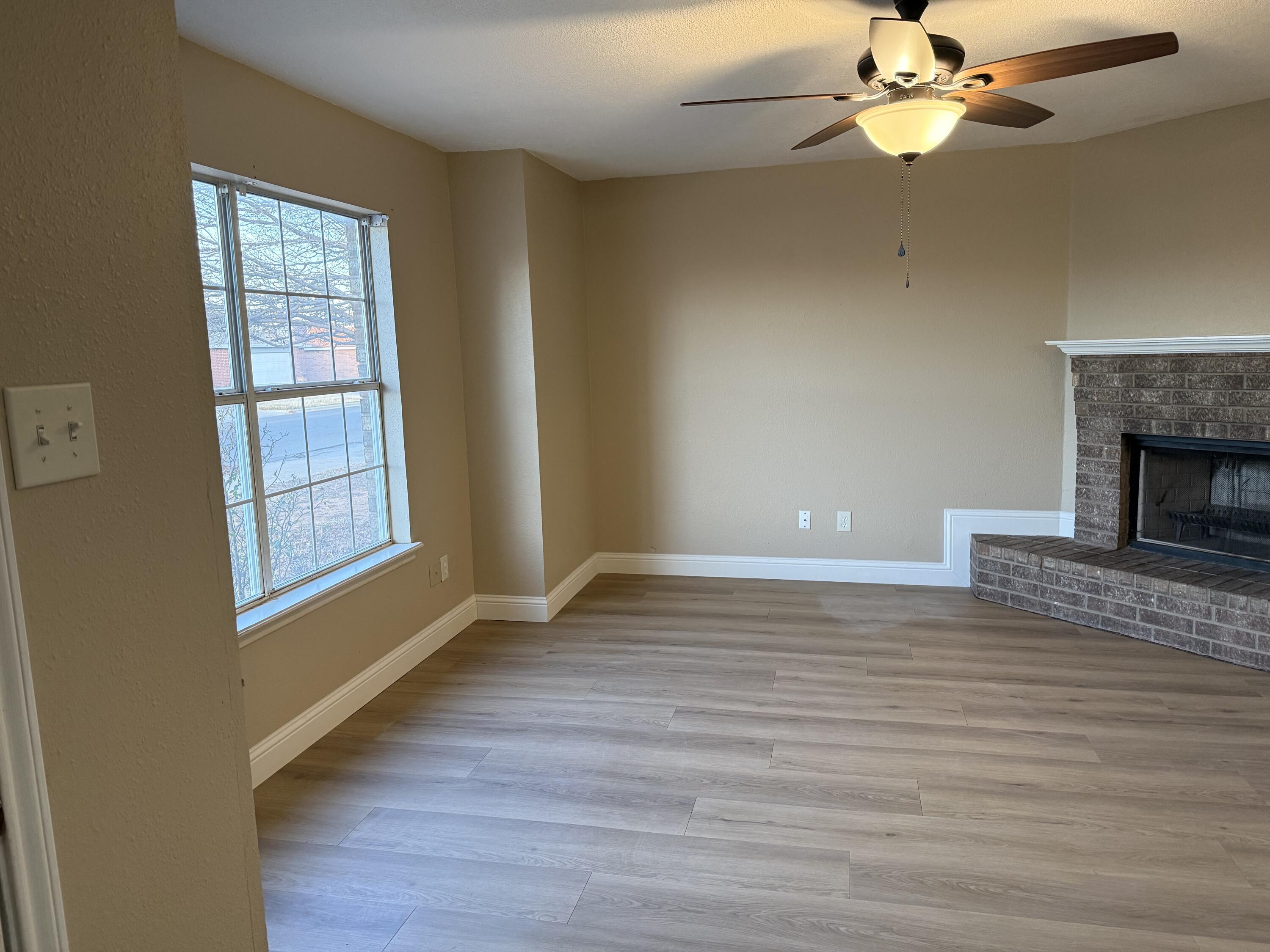 2523 110th Street Lubbock, TX 79423 - Photo 4 of 23 a view of an empty room with wooden floor fireplace and a window