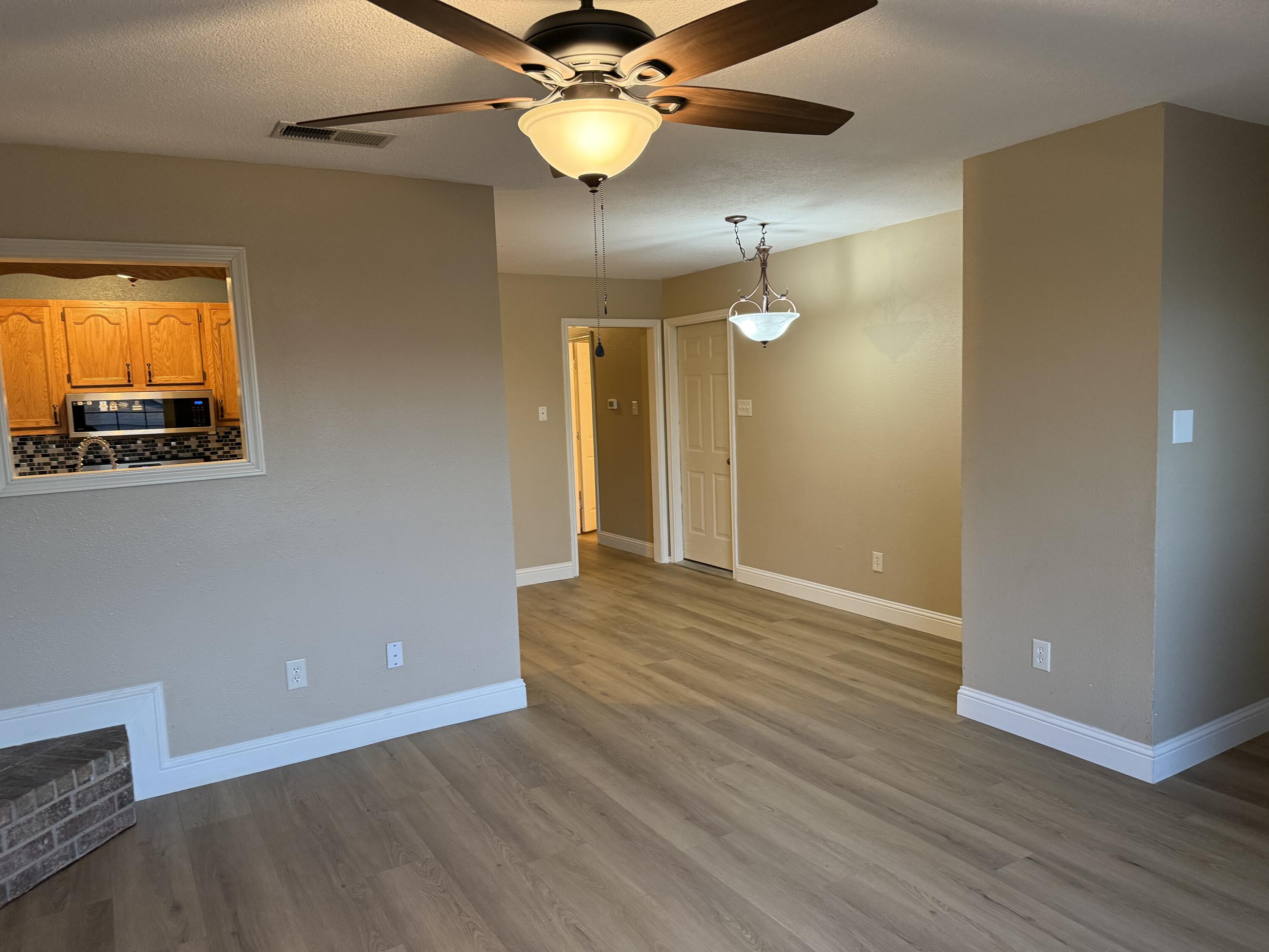 2523 110th Street Lubbock, TX 79423 - Photo 6 of 23 a view of an empty room with wooden floor and a ceiling fan