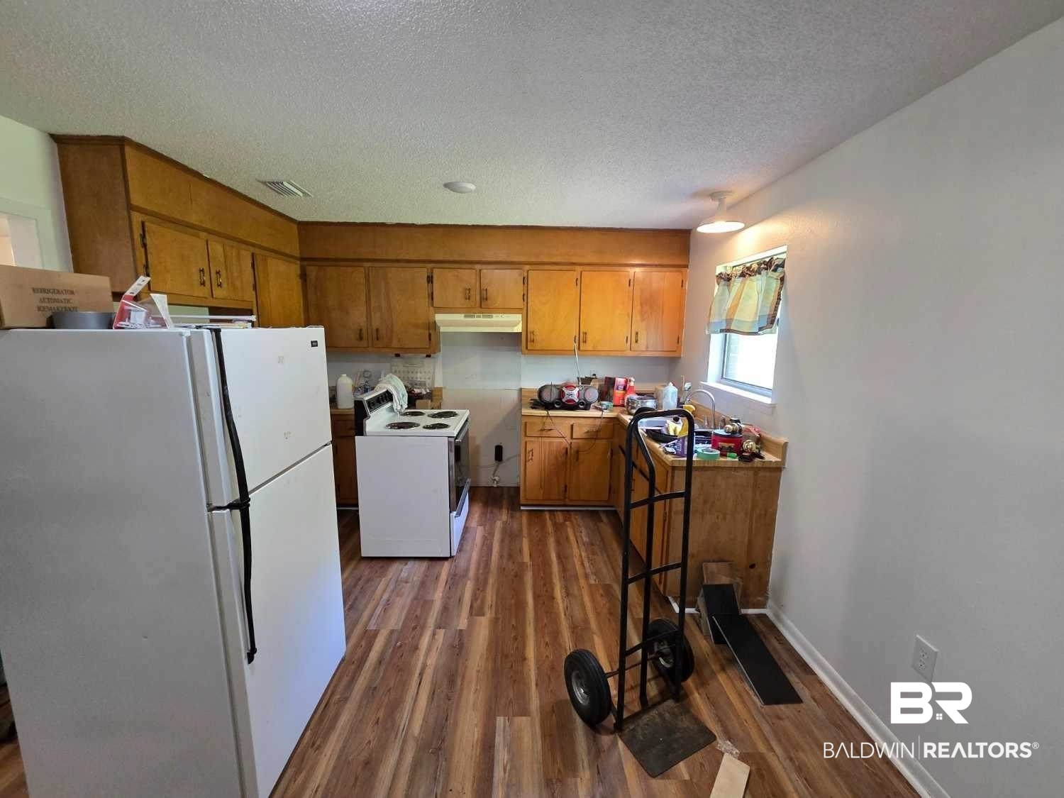 106 West 16th Street Bay Minette, AL 36507 - Photo 9 of 19 Kitchen with white appliances, brown cabinets, under cabinet range hood, dark wood finished floors, and a textured ceiling