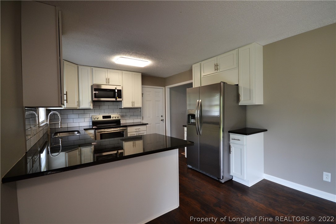 5201 Brookfield Road Fayetteville, NC 28303 - Photo 14 of 45 a kitchen with stainless steel appliances a refrigerator a stove a sink a washer and dryer