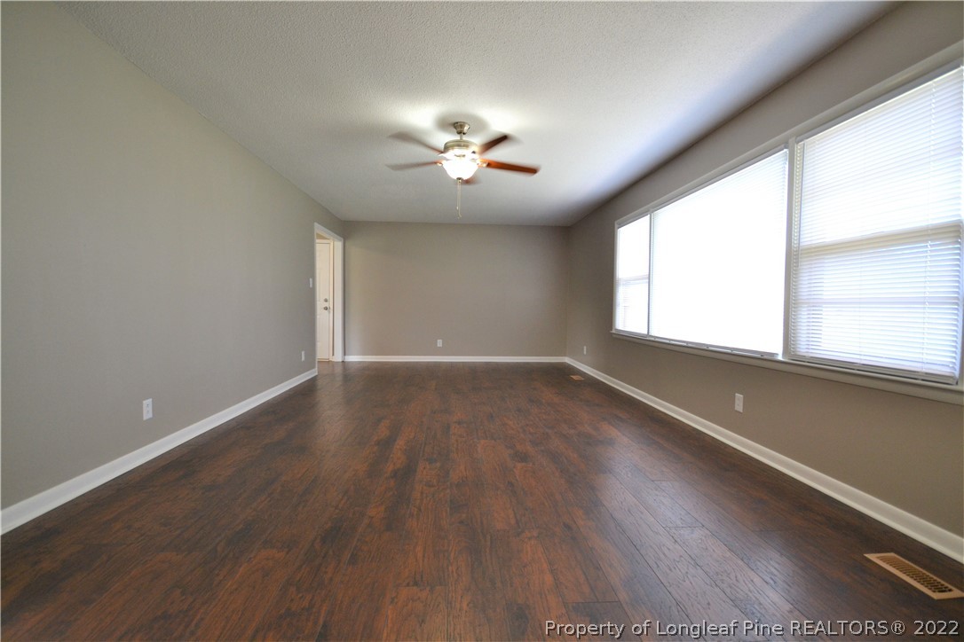5201 Brookfield Road Fayetteville, NC 28303 - Photo 10 of 45 an empty room with wooden floor chandelier fan and windows