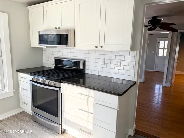 a kitchen with granite countertop a stove top oven a sink a counter space and cabinets