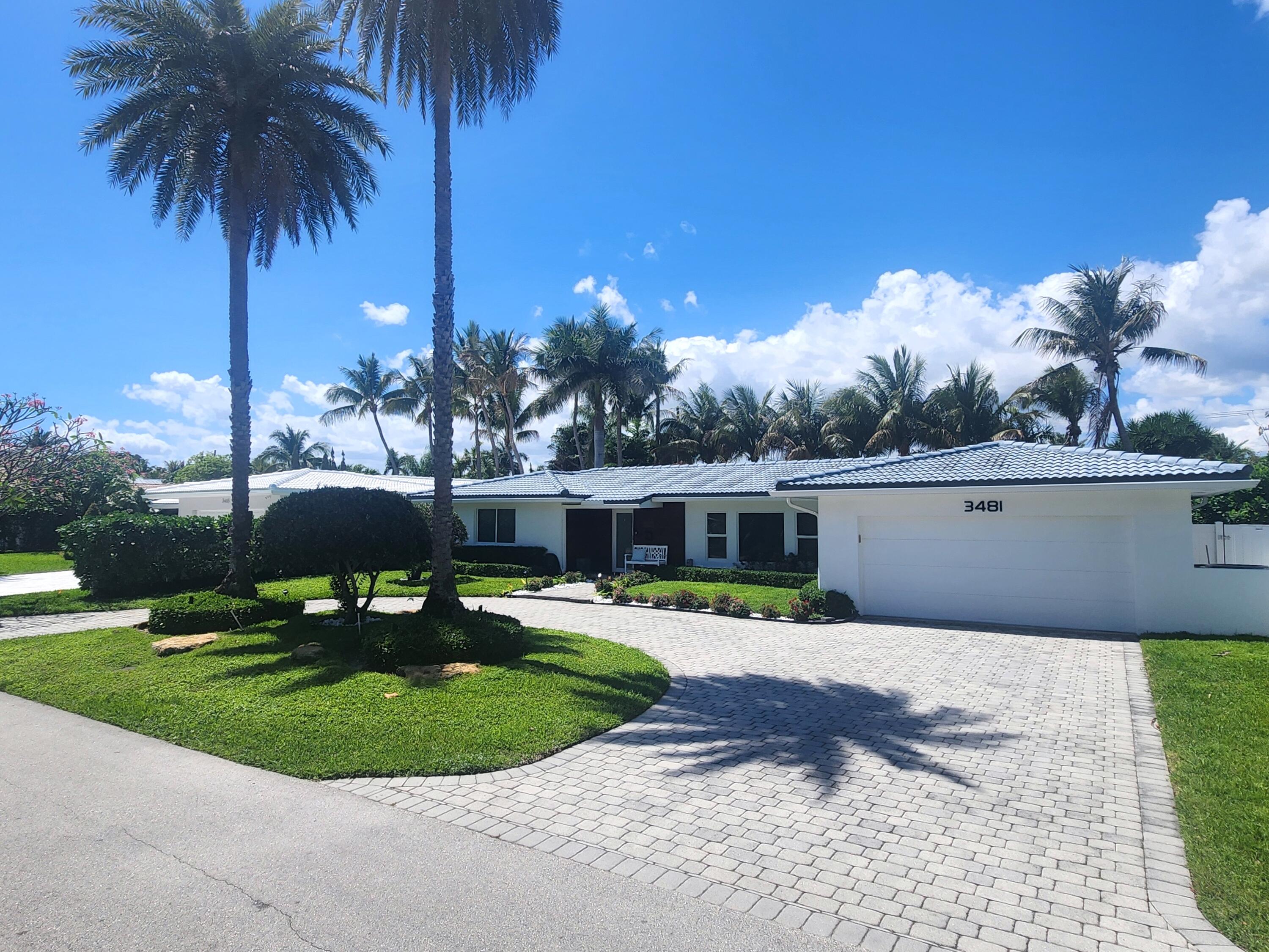 3481 Northeast 31st Avenue Lighthouse Point, FL 33064 - Photo 1 of 27 a front view of a house with a garden and a yard