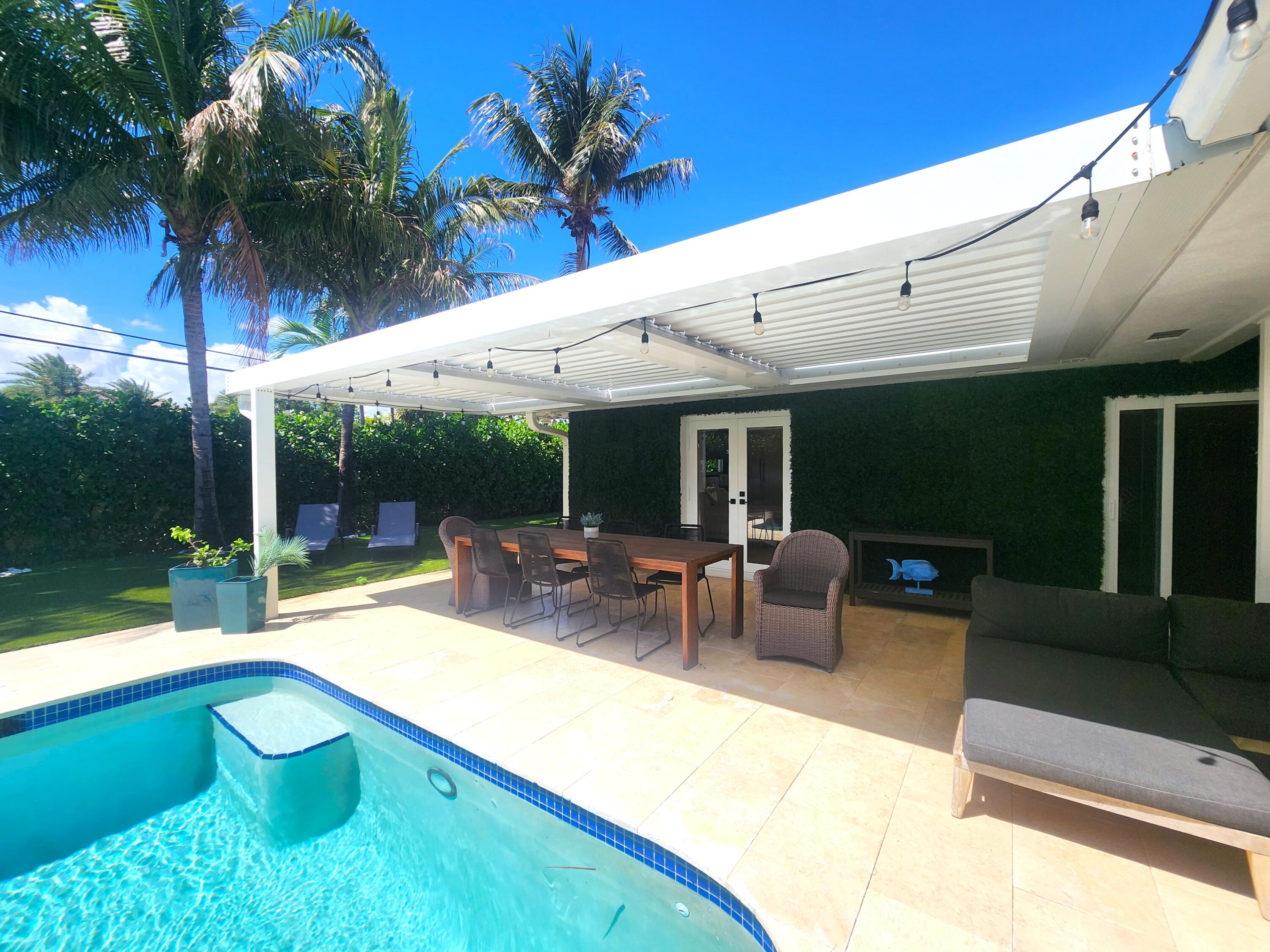 3481 Northeast 31st Avenue Lighthouse Point, FL 33064 - Photo 25 of 27 a view of a patio with table and chairs potted plants and palm tree