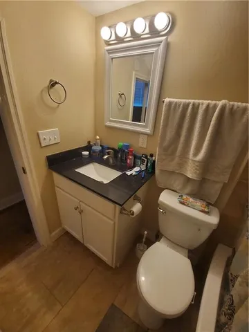 a bathroom with a granite countertop toilet sink and mirror