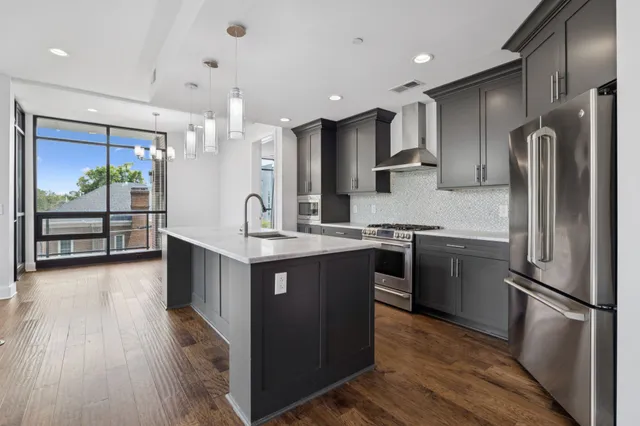 a kitchen with stainless steel appliances granite countertop a refrigerator a stove top oven and a wooden floors