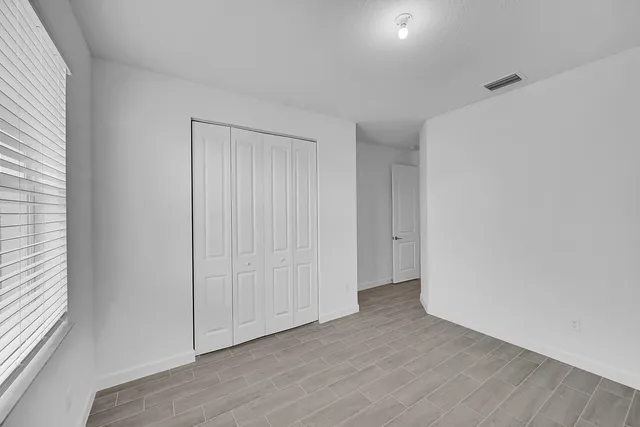 a view of an empty room with closet and a window