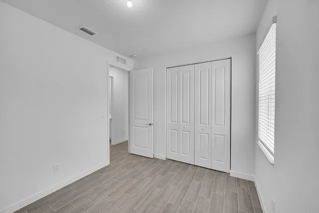 a view of an empty room with closet and a window