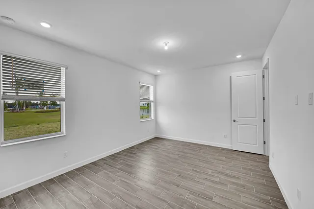 a view of an empty room with a window and wooden floor