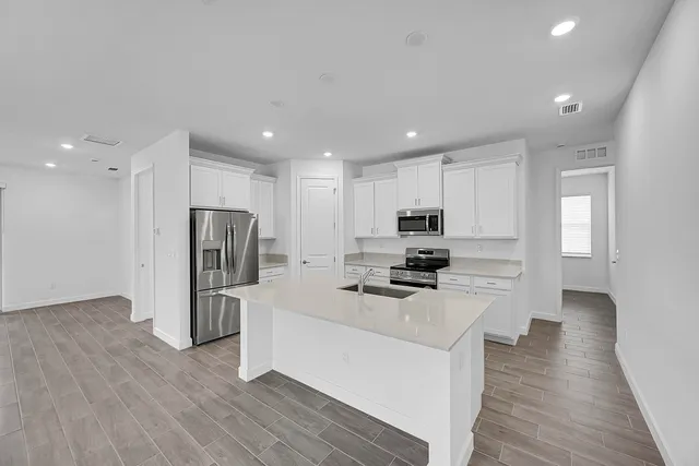 a kitchen with stainless steel appliances a refrigerator stove a sink and a oven with wooden floor