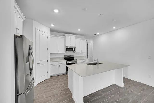 a kitchen with a refrigerator a sink and dishwasher with wooden floor