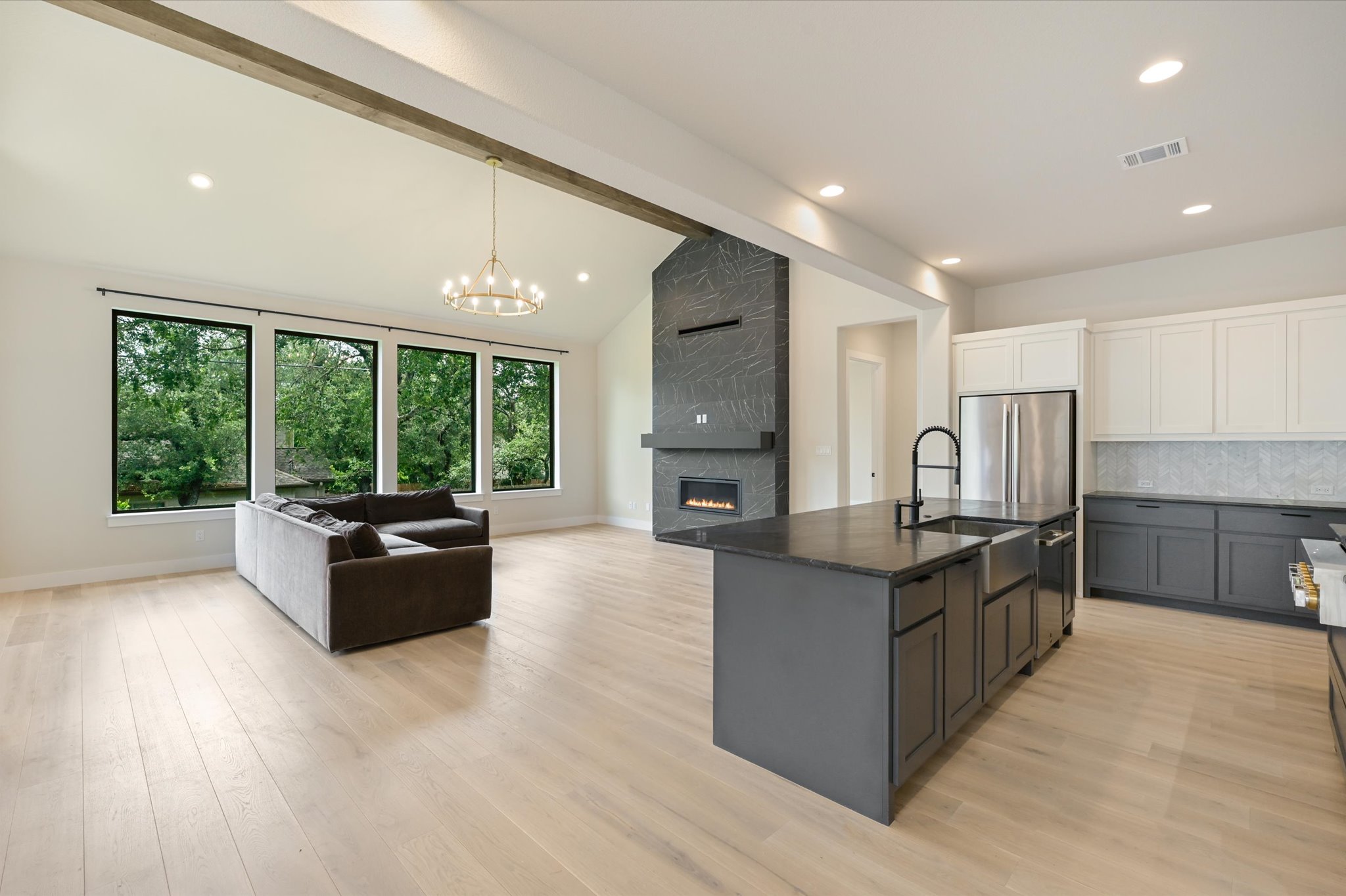 913 Presa Arriba Road Austin, TX 78733 - Photo 11 of 30 An open concept living area showcases vaulted ceilings, a modern fireplace, and a large kitchen island.