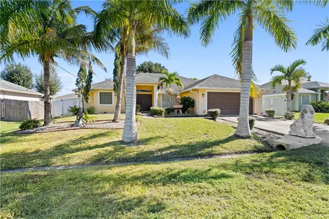 a view of a house with palm trees and a yard with swimming pool