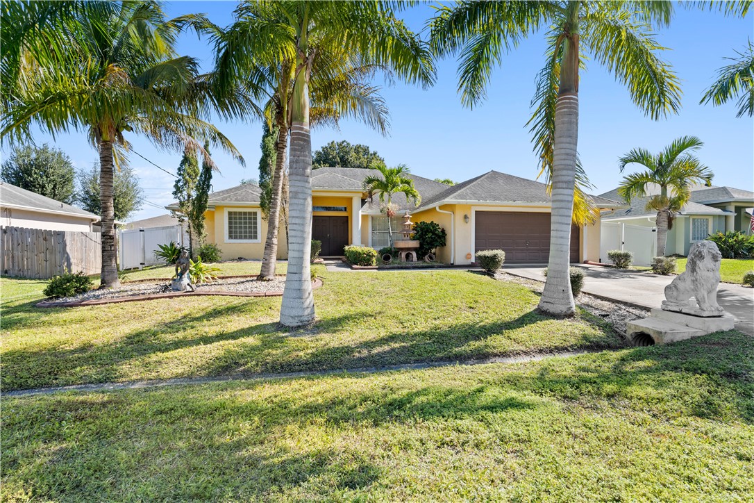 a view of a house with palm trees and a yard with swimming pool