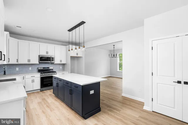 a kitchen with stainless steel appliances granite countertop a wooden cabinets a stove a sink and dishwasher a refrigerator with wooden floor