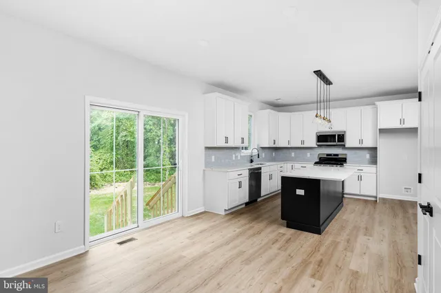 a kitchen with stainless steel appliances granite countertop a stove a sink and white cabinets with wooden floor