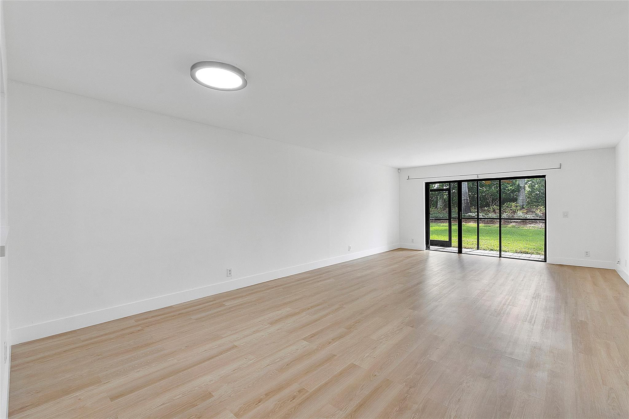 300 Racquet Club Road, Unit 105 Weston, FL 33326 - Photo 4 of 14 a view of an empty room with wooden floor and a window