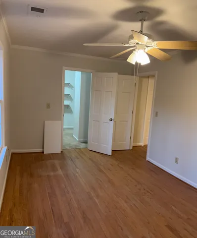 an empty room with wooden floor and fan