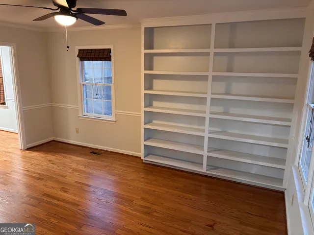 a view of an empty room with a window and wooden floor