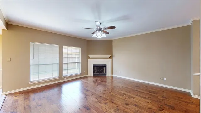 an empty room with chandelier fan and windows