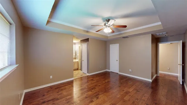 a view of an empty room with window and wooden floor