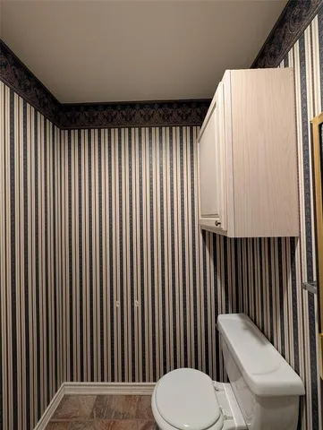 a bathroom with a toilet and a chair