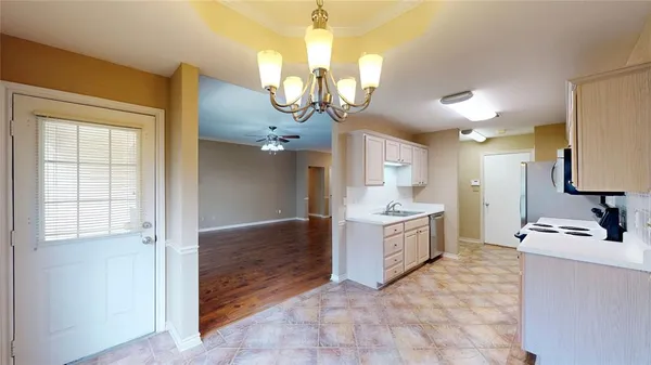a large white kitchen with a sink and dishwasher a stove top oven with wooden floor