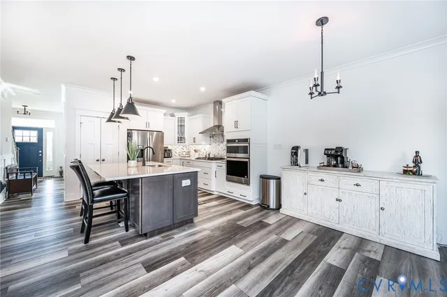 a kitchen with kitchen island a dining table chairs sink and cabinets