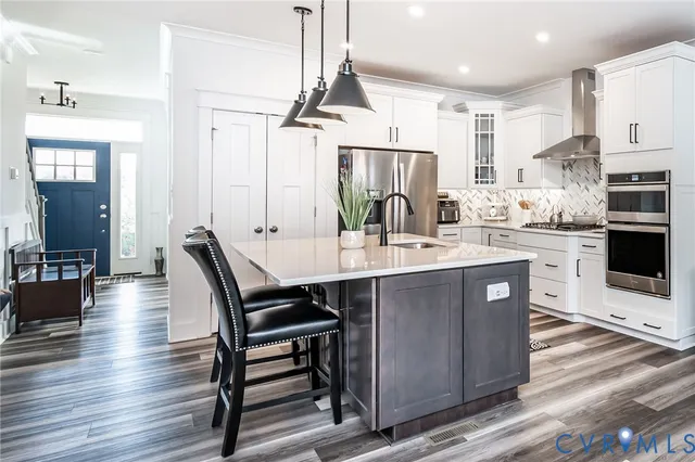 a kitchen with kitchen island a dining table chairs stainless steel appliances and cabinets