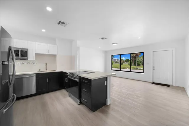 a kitchen with stainless steel appliances granite countertop a refrigerator a sink dishwasher a stove and a refrigerator with wooden floor