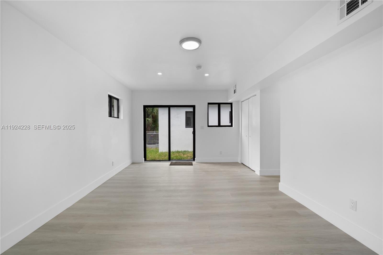 2983 Northwest 1st Street Pompano Beach, FL 33069 - Photo 3 of 28 a view of an empty room with wooden floor and a window