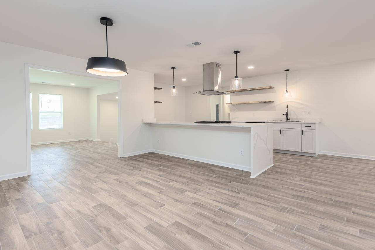 3160 Range Line Road Memphis, TN 38127 - Photo 9 of 28 Kitchen with pendant lighting, open shelves, light wood-style floors, a peninsula, and island range hood
