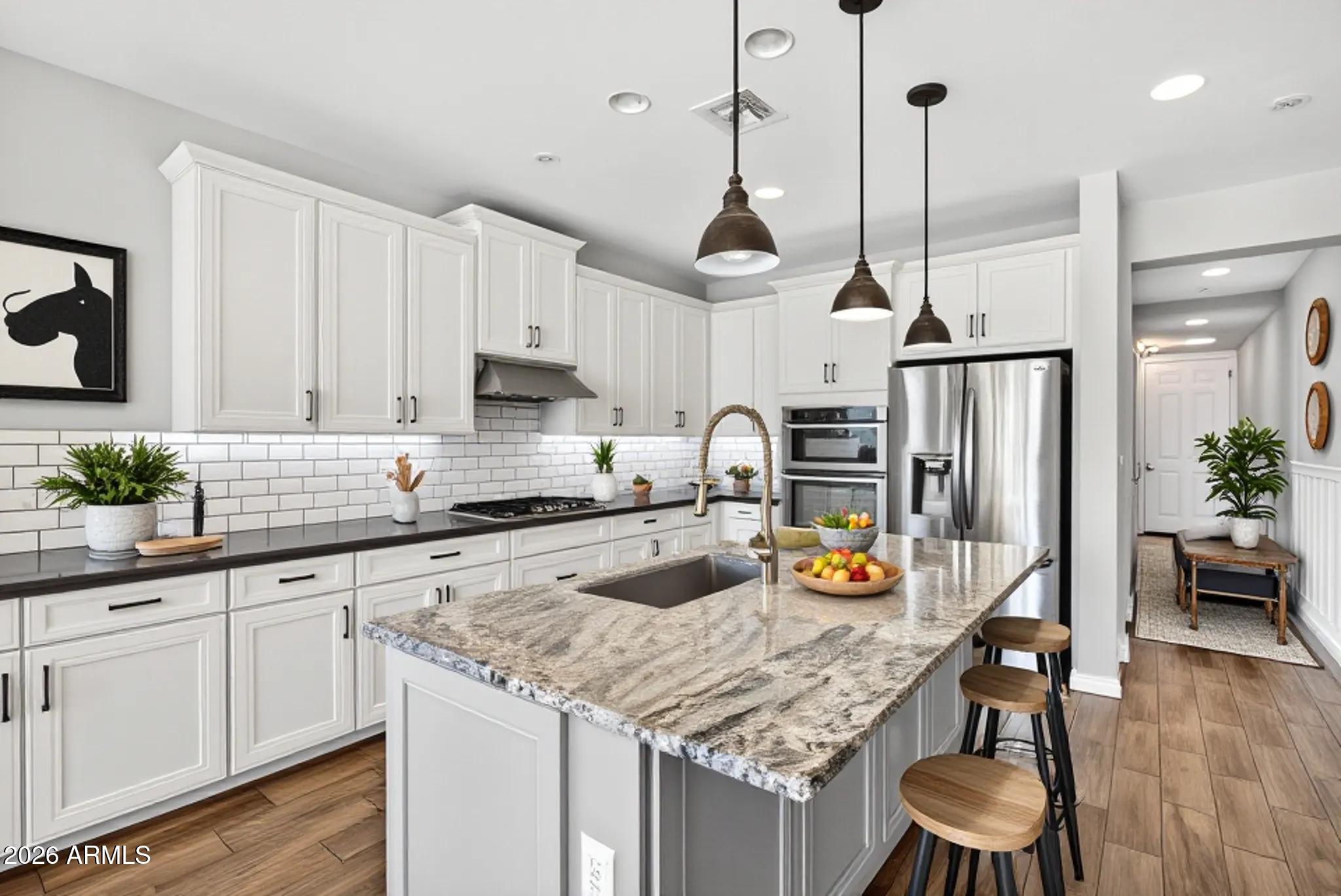 12124 West Peak View Road Peoria, AZ 85383 - Photo 7 of 38 a kitchen with stainless steel appliances granite countertop a sink a stove and chairs