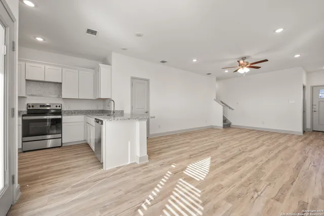 a view of kitchen with cabinets appliances wooden floor and a window