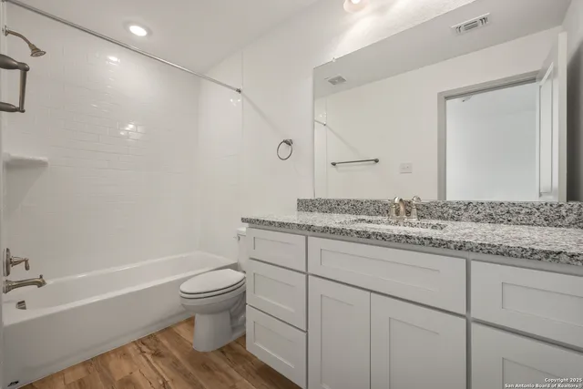 a bathroom with a granite countertop sink a toilet and a bathtub
