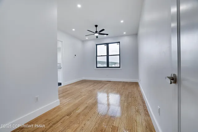 a view of an empty room with wooden floor and a window