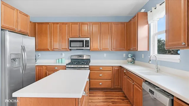 a kitchen with stainless steel appliances granite countertop a stove top oven a sink dishwasher and a refrigerator with wooden cabinets