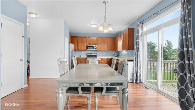 a kitchen with stainless steel appliances granite countertop a stove a refrigerator a sink a dining table and chairs with wooden floor