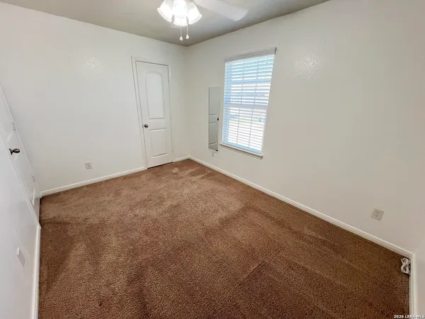 an empty room with a chandelier fan and windows