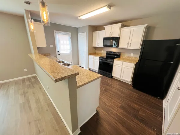 a kitchen with granite countertop a refrigerator a stove top oven a sink dishwasher and wooden floor