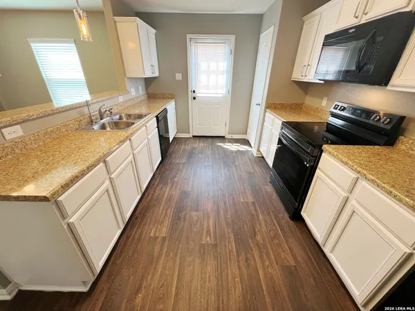 a kitchen with a sink and wooden floor
